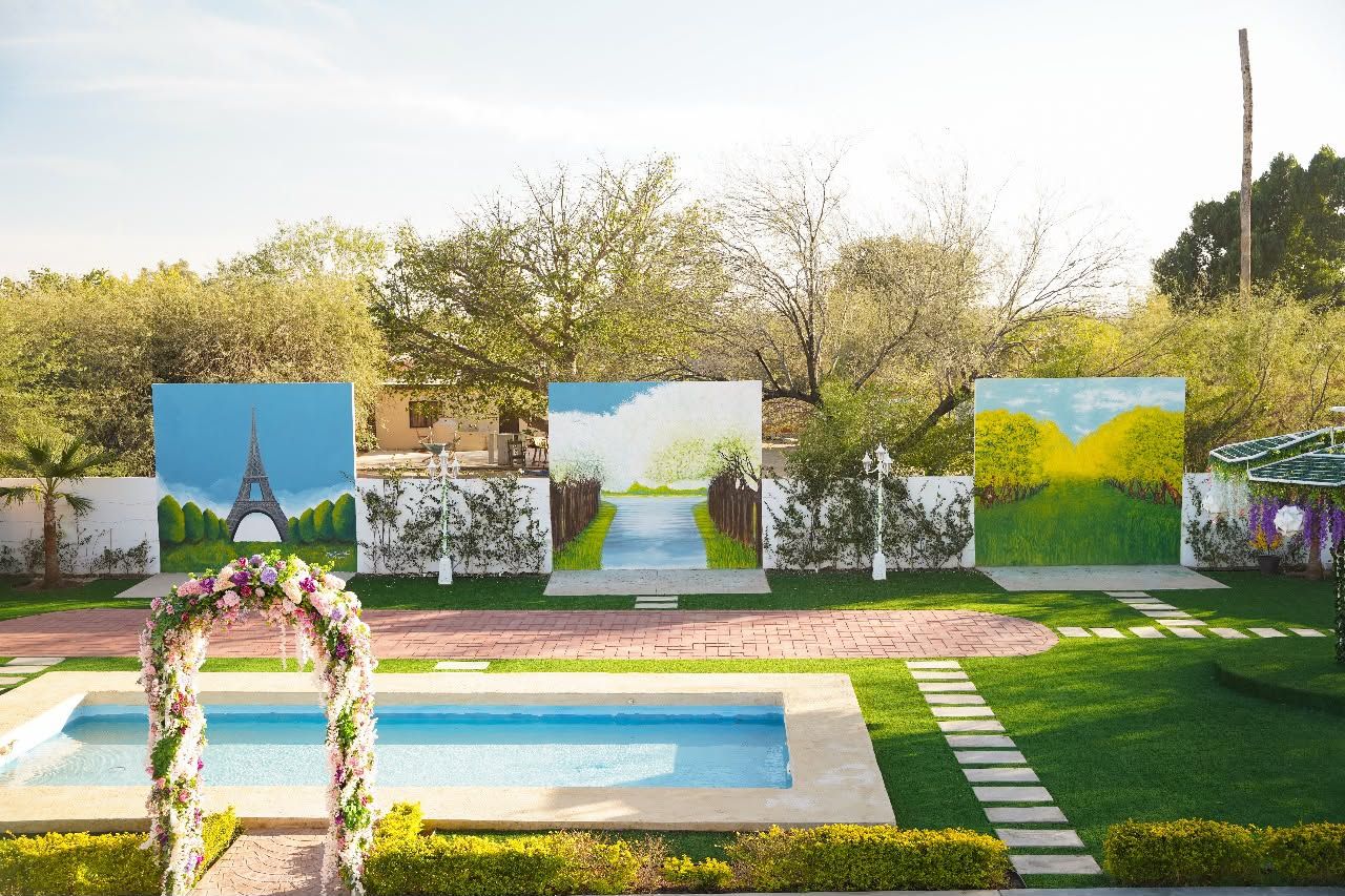 Alberca con arco de flores y murales alrededor