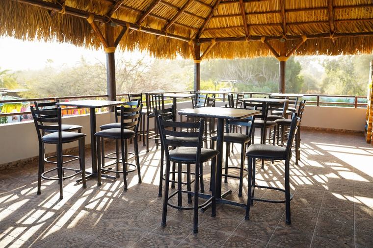 Terraza con techo de palma y mesas altas